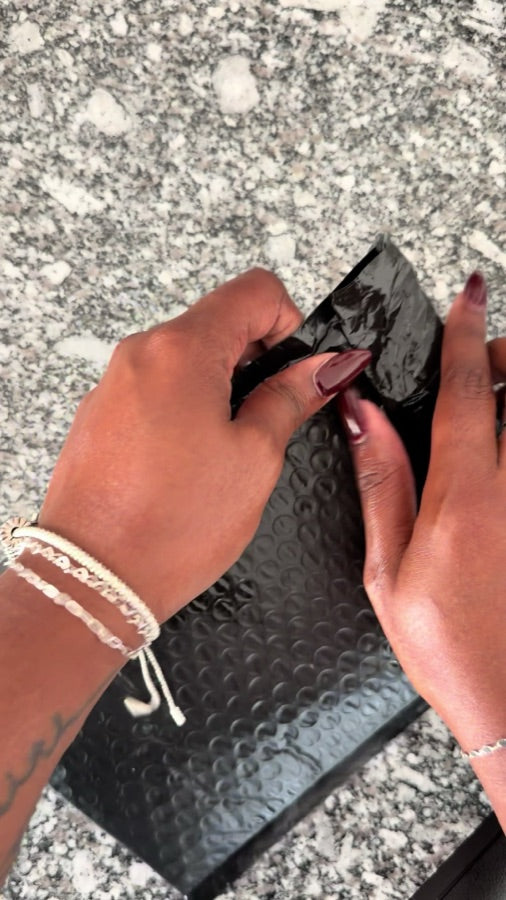 TikTok by @sydneyandreaa_: two hands opening a black padded mailer on a granite counter